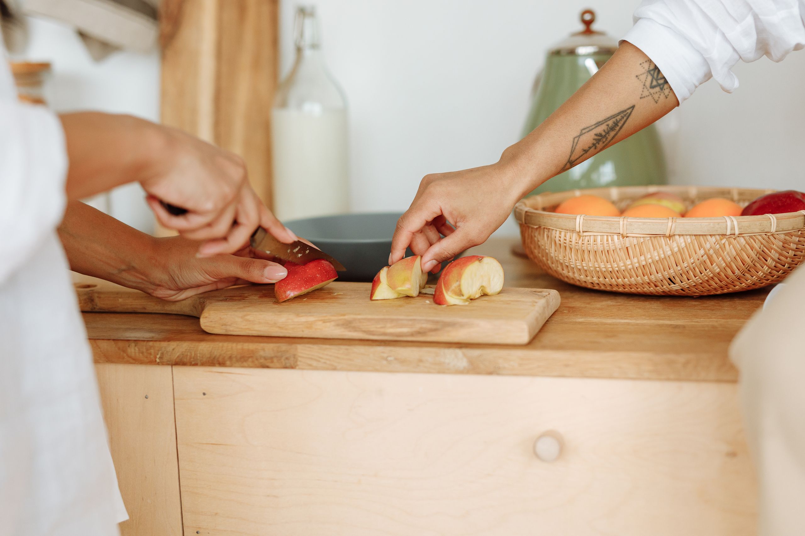 Close-up of hands cutting apples on a wooden board in a warm kitchen environment.